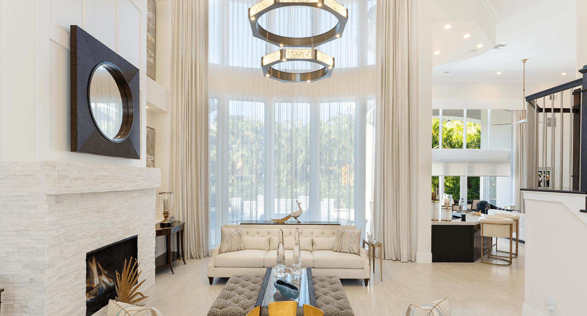 Spacious living room with floor-to-ceiling white drapery and large chandeliers.